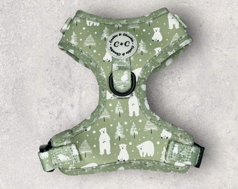 May include: A dog harness with a light green background and a repeating pattern of white polar bears and Christmas trees. The harness has black hardware and the brand name "Cookie & Chumble" is printed on the front.