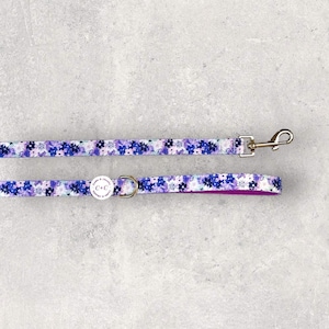 May include: Purple and white floral dog lead with a silver clip and a small round tag that says "C&C".