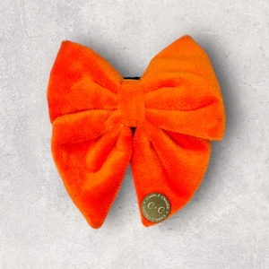 May include: A bright orange fluffy bow tie with a gold metal charm that says "C&C" in the centre.