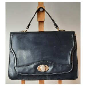 Sac à main vintage en cuir bleu marine avec poignée supérieure, style structuré des années 1960, fermoir tourniquet doré, style rétro classique et élégant, sac à main féminin iconique