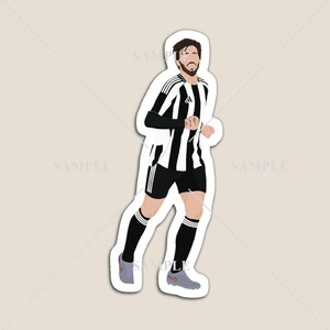 May include: A sticker featuring a stylized illustration of a soccer player in a black and white striped jersey, black shorts, and gray shoes. The player is running with a determined expression. The sticker has a white border.