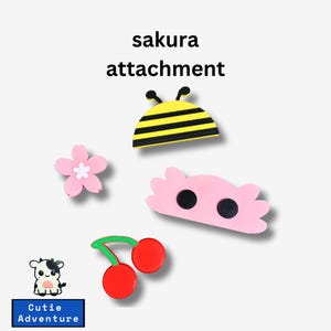 Op de afbeelding: Een set van vier kleurrijke, cartoonachtige strijklabels. De labels bevatten een bij, een kers, een bloem en een wolk met twee ogen. De labels zijn gemarkeerd met "sakura attachment".