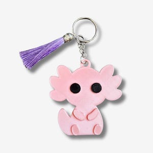 May include: A pink axolotl keyring with black eyes and a purple tassel. The keyring is attached to a silver key ring and chain. The axolotl is a stylized, cartoon-like design.