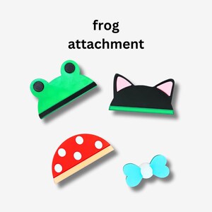 Op de afbeelding: Vier verschillende opties voor frog-bevestigingen: een groene kikker, een zwarte kat, een rode en witte paddenstoel en een blauwe strik.