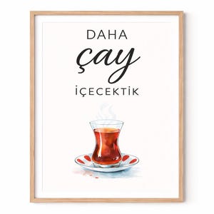 Könnte beinhalten: Ein gerahmter Kunstdruck mit einer Aquarellillustration eines Teeglases auf einer Untertasse. Der Druck enthält den türkischen Text "DAHA çay içecektik" in schwarzer Schrift. Der Rahmen ist aus hellem Holz.