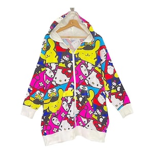 May include: A long, zip-up hoodie featuring a colorful pattern of cartoon characters in pink, yellow, blue, and white. The hoodie has a white hood lining, cuffs, and hem. The zipper is white.
