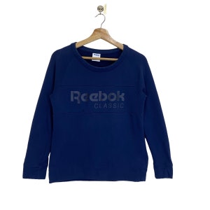 Op de afbeelding: Een marineblauw sweatshirt met lange mouwen met het Reebok Classic logo op de voorkant.
