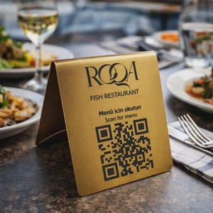 May include: A gold metal table sign for a fish restaurant. The sign has the restaurant's logo and the words "FISH RESTAURANT" printed in black. It also includes a QR code and the text "Scan for menu".