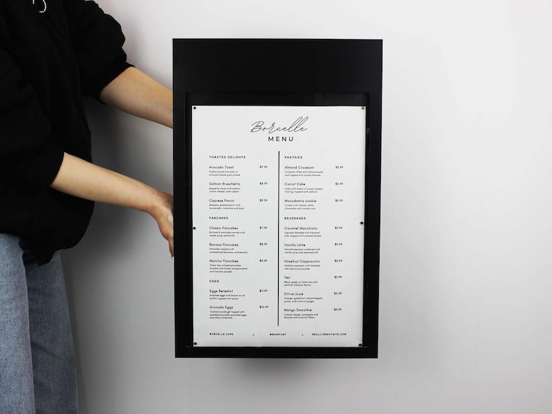 Black metal restaurant menu display box shown from the front to demonstrate its rectangular frame and printed menu insert. Wall mounted commercial menu holder for cafes, bakeries and restaurant entrance signage.