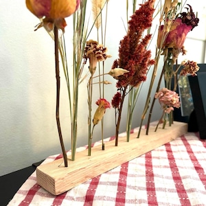 Peut inclure: Arrangement de fleurs s&eacute;ch&eacute;es dans un support en bois. L'arrangement comprend des roses s&eacute;ch&eacute;es, des &oelig;illets et des herbes dans des tons de rose, rouge et beige.