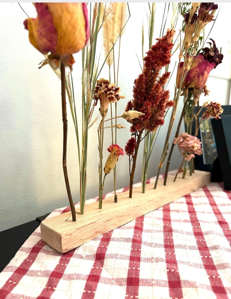 Peut inclure: Arrangement de fleurs s&eacute;ch&eacute;es dans un support en bois. L'arrangement comprend des roses s&eacute;ch&eacute;es, des &oelig;illets et des herbes dans des tons de rose, rouge et beige.