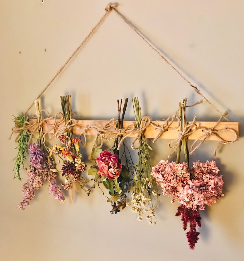 Peut inclure: Des fleurs s&eacute;ch&eacute;es de diff&eacute;rentes couleurs et de diff&eacute;rents types sont accroch&eacute;es &agrave; un support en bois avec de la ficelle. Les fleurs comprennent de la lavande, du rose, du violet et du blanc.