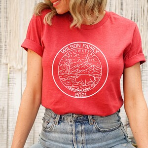 May include: Red t-shirt with a white graphic of a Yellowstone National Park logo. The logo includes a bison, mountains, a geyser, and the text "Wilson Family Yellowstone National Park 2021".