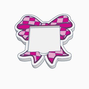 Puede incluir: Un marco en forma de lazo rosa y blanco con un patrón de cuadros. El marco tiene un borde blanco y un centro cuadrado en blanco. El diseño del lazo es en tonos de rosa y blanco.