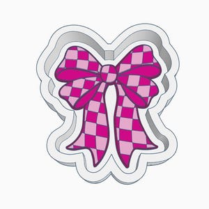May include: A pink bow-shaped cookie cutter with a checkered pattern. The bow has a scalloped outline and a detailed design, perfect for baking themed treats. The bow's color scheme includes shades of pink and white.