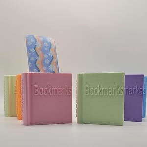 May include: Five small, colorful bookends with the word "Bookmarks" printed on them. The bookends are in shades of pink, green, purple, orange, and yellow.