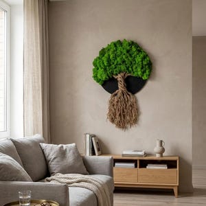 Könnte beinhalten: Runde Wanddekoration mit einem Baum aus grünem Moos. Das Laub des Baumes ist leuchtend grün, vor einem dunklen, kreisförmigen Hintergrund. Stamm und Wurzeln bestehen aus naturfarbenem Seil und wirken strukturiert.