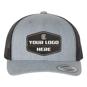 May include: A gray and black trucker hat with a black leather patch that says "YOUR LOGO HERE" and a white letter "B" inside a circle.