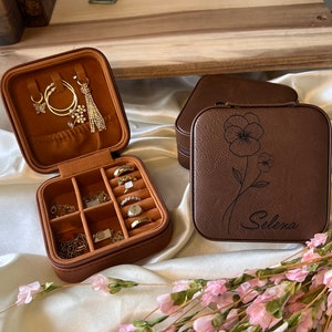 May include: Two brown faux leather jewellery boxes. One box has compartments for rings and earrings. The other box has a floral design and the name "Selena" engraved on the front.
