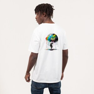 May include: A white t-shirt with a colorful graphic of a globe dripping paint on a person standing underneath. The globe is painted in shades of blue, green, yellow, orange, red, and purple.