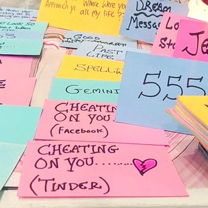 May include: A collection of colorful sticky notes with handwritten messages. Notes include phrases like "Jealous," "Marry Me," and "Cheating on You." Numbers and symbols are also present, suggesting a theme of divination or fortune-telling.