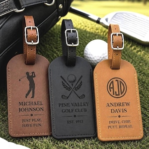 Peut inclure: Trois étiquettes de bagage rectangulaires avec des lanières en cuir réglables et des boucles argentées. L'étiquette de gauche est marron avec une silhouette de golfeur et le texte Michael Johnson, Just Play. Have Fun. Celle du centre est noire avec des clubs de golf et Pine Valley Golf Club, Est. 1913. Celle de droite est beige avec les initiales AJD, Andrew Davis, et Drive. Chip. Putt. Repeat.