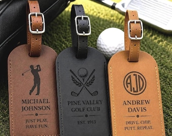 May include: Three rectangular luggage tags with adjustable leather straps and silver buckles. The left tag is brown with a golfer silhouette and text reading Michael Johnson, Just Play. Have Fun. The center is black with golf clubs and Pine Valley Golf Club, Est. 1913. The right is tan with initials AJD, Andrew Davis, and Drive. Chip. Putt. Repeat.
