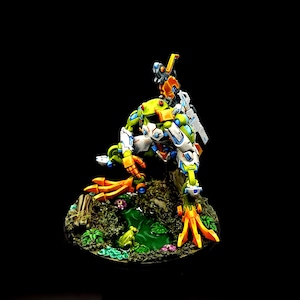 May include: A green, white, and orange robot frog figurine with a small robot on its back. The robot frog is sitting on a green base with a small pond and flowers.