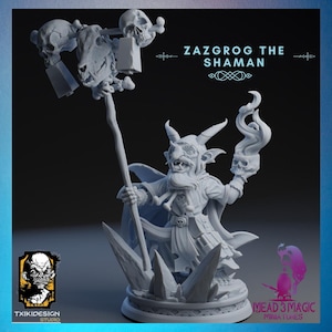Puede incluir: Una figura miniatura gris y detallada de un chamán goblin sosteniendo un bastón y una calavera. La figura está de pie sobre una base con un diseño de cristal. El texto "Zazgrog the Shaman" está escrito sobre la figura.