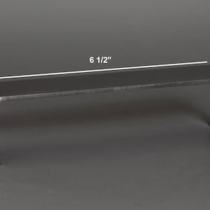 Puede incluir: Un expositor negro en forma de U. El expositor mide 16,5 cm de largo, 4,1 cm de alto y 3,8 cm de profundidad. Los bordes son redondeados. El expositor est&aacute; hecho de un material oscuro y s&oacute;lido y es adecuado para exhibir objetos peque&ntilde;os.