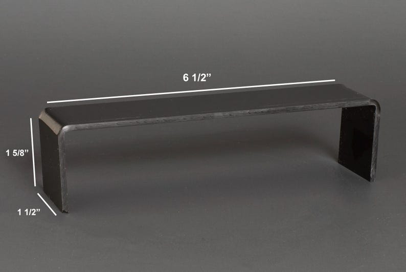 Puede incluir: Un expositor negro en forma de U. El expositor mide 16,5 cm de largo, 4,1 cm de alto y 3,8 cm de profundidad. Los bordes son redondeados. El expositor est&aacute; hecho de un material oscuro y s&oacute;lido y es adecuado para exhibir objetos peque&ntilde;os.