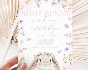 Puede incluir: Una invitación a una fiesta de bienvenida al bebé con un fondo rosa y detalles florales. La invitación presenta un lindo conejito con una corona de flores y el texto "SOME BUNNY is on the way!"  Únete a nosotros para una fiesta de bienvenida al bebé en honor a Sarah Mae. 17 de abril de 5 a 6 pm en la casa de Sarah, 5 Rodeo Drive LA. RSVP a Mia 123-456-7890.