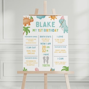 May include: A colourful printable first birthday milestone chart for a boy named Blake. The chart features a dinosaur theme with illustrations of dinosaurs, a palm tree, and a sun. It includes information about Blake's birth stats, favourite songs, foods, books, and what he can do.