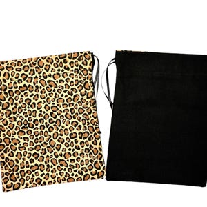 Pode incluir: Duas sacolas com cordão. Uma apresenta um padrão de estampa de leopardo em tons de marrom e bege. A outra sacola é preta lisa. Ambas as sacolas têm cordões pretos.