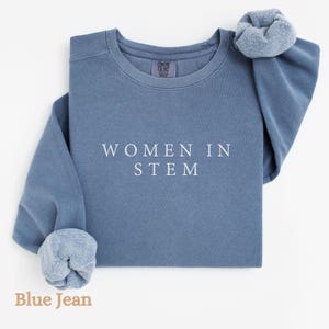 May include: A blue jean sweatshirt with the text "WOMEN IN STEM" printed in white on the front.