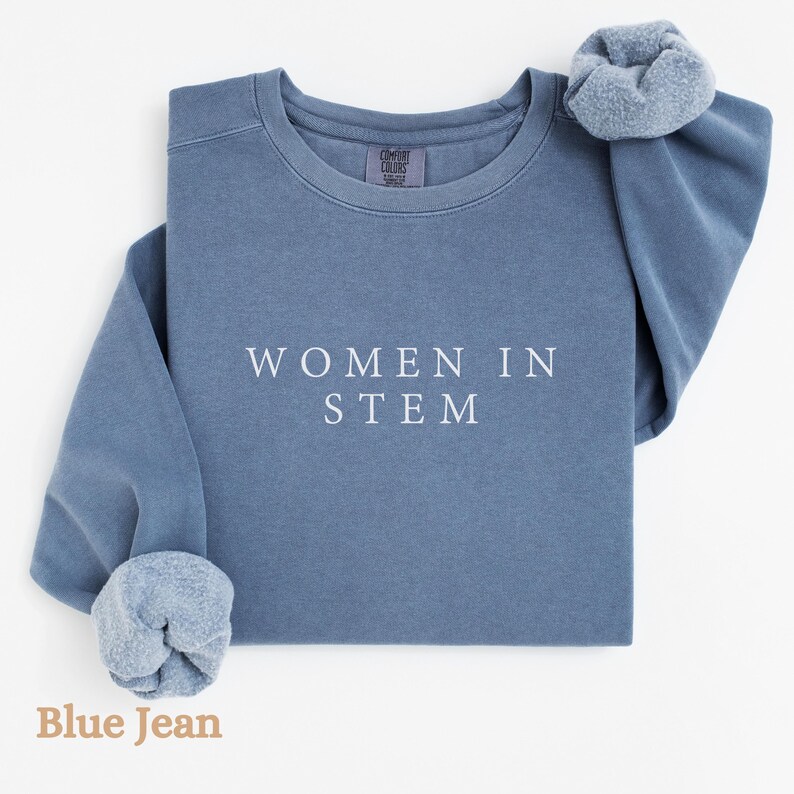 May include: A blue jean sweatshirt with the text "WOMEN IN STEM" printed in white on the front.
