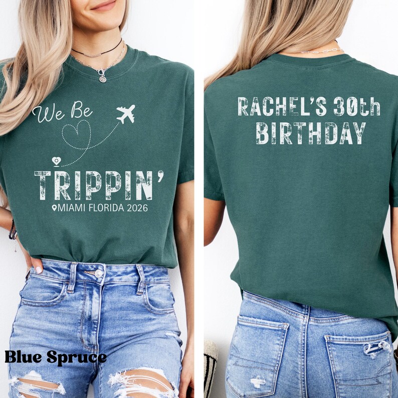 May include: Teal-colored t-shirt with the text "We Be Trippin' Miami Florida 2026" and a graphic of a plane and heart on the front. The back of the shirt says "Rachel's 30th Birthday" in white letters. The shirt is paired with blue jeans.
