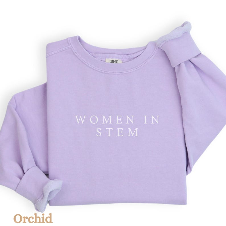May include: A lavender sweatshirt with the text "Women in STEM" printed in white on the front.