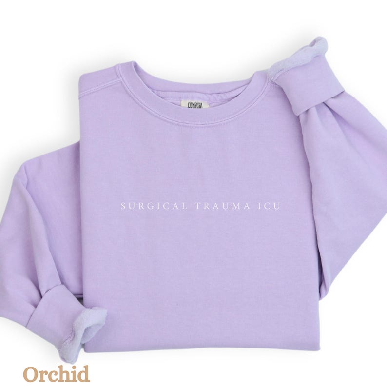 May include: A lavender sweatshirt with the text "SURGICAL TRAUMA ICU" printed in white on the front.