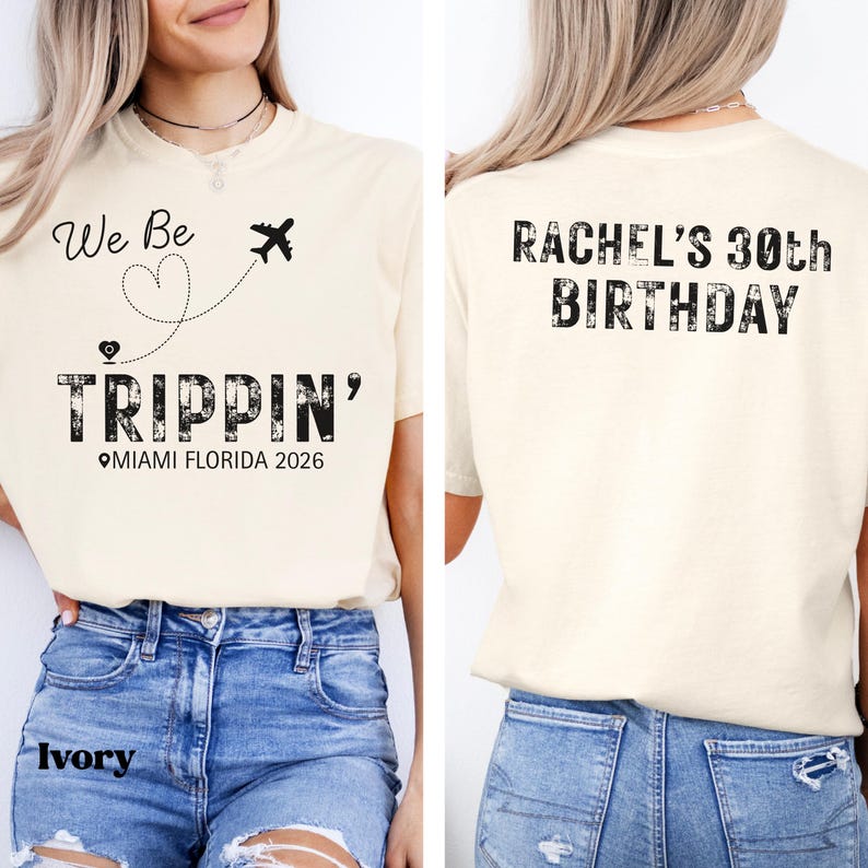 May include: Ivory-colored t-shirt with the text "We Be Trippin' Miami Florida 2026" on the front, featuring a heart and airplane graphic. The back of the shirt says "Rachel's 30th Birthday".