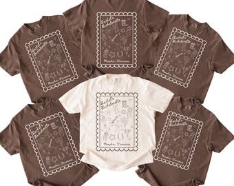 May include: Six brown t-shirts with white text and graphics. The shirts feature a design with the text "Rachel's Bachelorette" and various western-themed illustrations. The text "Memphis, Tennessee" is also included on each shirt.