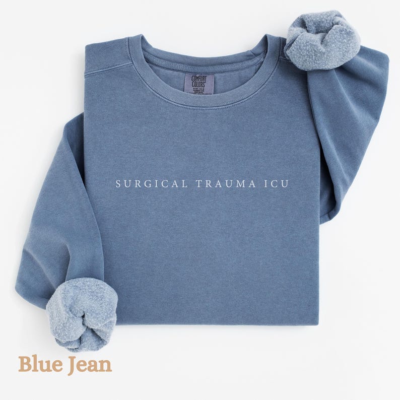 May include: A blue jean sweatshirt with the text "SURGICAL TRAUMA ICU" printed in white on the front.