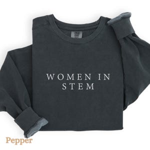 May include: A dark grey sweatshirt with the text "WOMEN IN STEM" printed in white on the front.