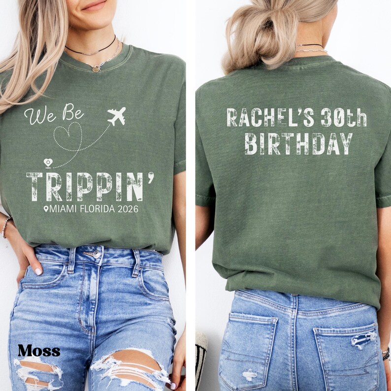 May include: Moss green t-shirt with the text "We Be Trippin' Miami Florida 2026" on the front and "Rachel's 30th Birthday" on the back. The shirt features a crew neck and short sleeves. The model is wearing blue jeans.