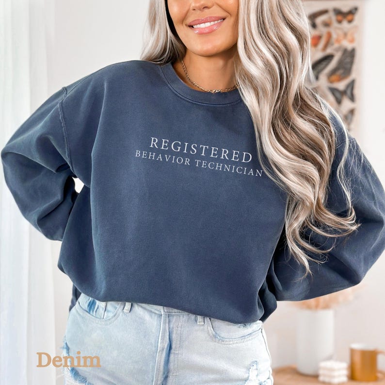 Pode incluir: Uma camisa de moletom azul escura com o texto "REGISTERED BEHAVIOR TECHNICIAN" impresso em branco na frente.