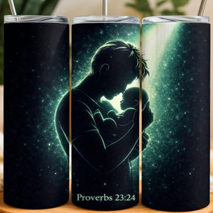 May include: A set of three black insulated tumblers with a celestial design. The central tumbler features a silhouette of a parent holding a baby, with a glowing green light. The text "Proverbs 23:24" is at the bottom.