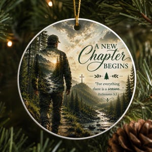 May include: A round ceramic ornament featuring a person walking through a forest landscape toward a distant cross. The text reads A NEW CHAPTER BEGINS and For everything there is a season Ecclesiastes 3:1. The design includes a golden string loop.
