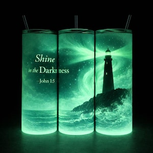 May include: Three green tumblers with black straws. Each tumbler has a glowing design of a lighthouse on a rocky shore, with the text "Shine in the Darkness - John 1:5". The design glows in the dark.