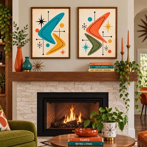 May include: Two framed wall art prints featuring abstract boomerang shapes in teal, yellow, orange, and olive green, accented with starbursts and circles on a cream background. The prints are displayed above a fireplace mantel with books.