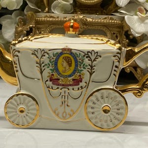 Tetera antigua con la imagen del carruaje real de la coronación de la reina Isabel. Caja de música.